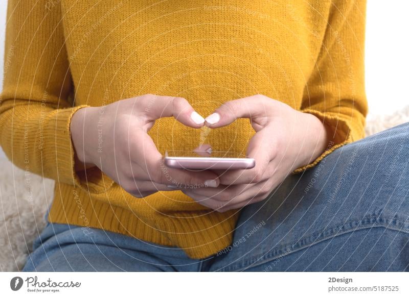 Nahaufnahme einer Frau mit gelbem Pullover, die ein Mobiltelefon benutzt Trikot Mobile Telefon Hände Tippen Senf Hand Person benutzend Technik & Technologie