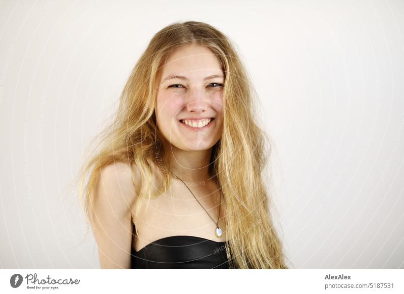 Nahes Portrait einer jungen, blonden Frau, die  vor einem weißen Hintergrund steht frisch Blick in die Kamera Erwartung drinnen Selbstbewußt weiblich charmant
