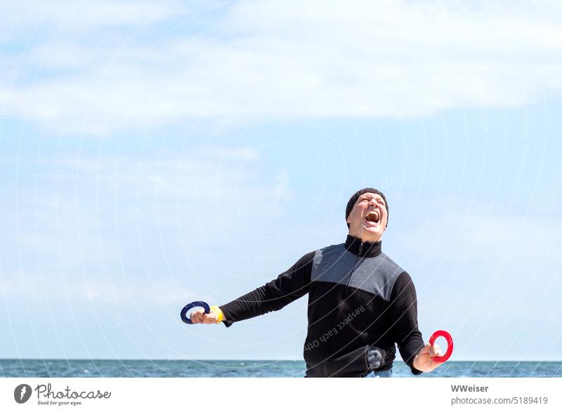 Ein Mann lenkt einen Drachen am Strand und empfindet Begeisterung, gemischt mit großer Spannung Emotion Spaß Freude lachen aufpassen lenken Meer Wind Wetter