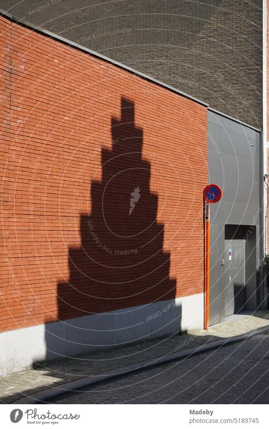 Schatten eines historischen Treppengiebel auf einer Fassade aus rotbraunem Backstein im Sonnenschein in den Gassen der Altstadt von Brügge in Westflandern in Belgien