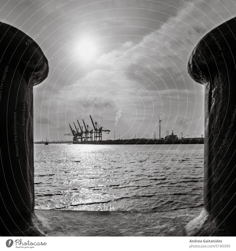 Blick durch zwei Poller am Hafen von Hamburg auf Hafenkräne, Wasser und Himmel, 1:1, quadratisch , schwarz-weiß Blick hindurch zwischen Hamburger Hafen am Tage