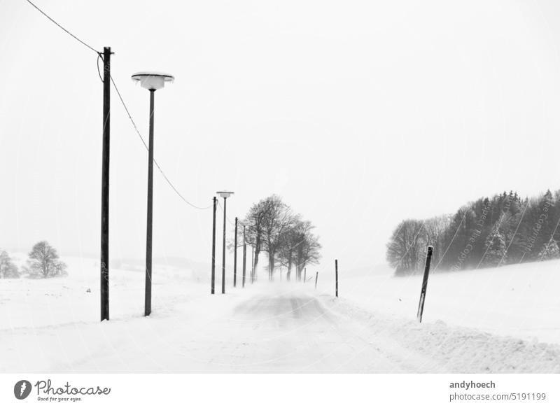 Schneebedeckte Landstraße bergab in der Mitte Deutschlands allein Asphalt Schneesturm kalt kalte Temperatur Konzept Regie Erkundung Entdecker weitergeben