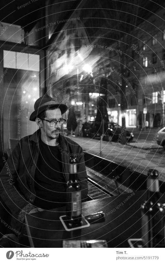 Mann mit Hut und Brille an einem Tisch in einer Bar Nacht Fenster Bart Prenzlauer Berg Herbst kastanienallee s/w bnw Schwarzweißfoto Stadt Stadtzentrum Berlin