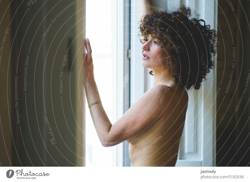 Junge nackte Frau steht am Fenster Model sinnlich erotisch Afro-Look verführerisch sexy feminin Körper Windstille Verlockung jung charmant besinnlich heimwärts
