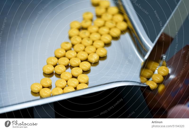 Selektiver Fokus auf gelbe Tabletten Pillen auf rostfreiem Tablett mit unscharfer Hand des Apothekers oder Apothekentechnikers, der die Pillen in einen Plastikreißverschlussbeutel zählt. Verschreibungspflichtige Medizin. Medizinische Gesundheitsfürsorge.