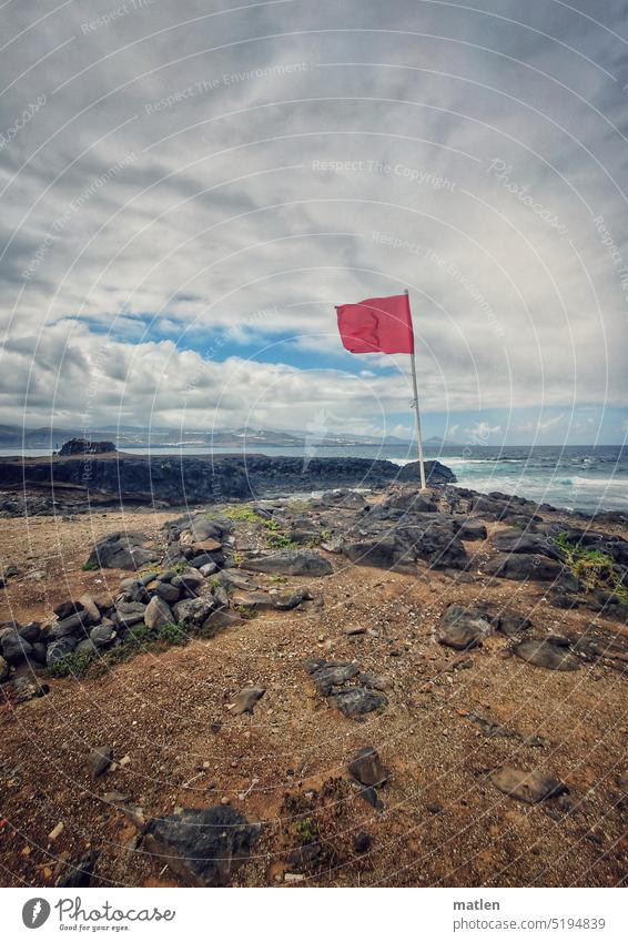 Rote Fahne an der Küste Himmel Wolken Sturm Felsen Meer Blauer Himmel Landschaft Farbfoto Außenaufnahme Menschenleer