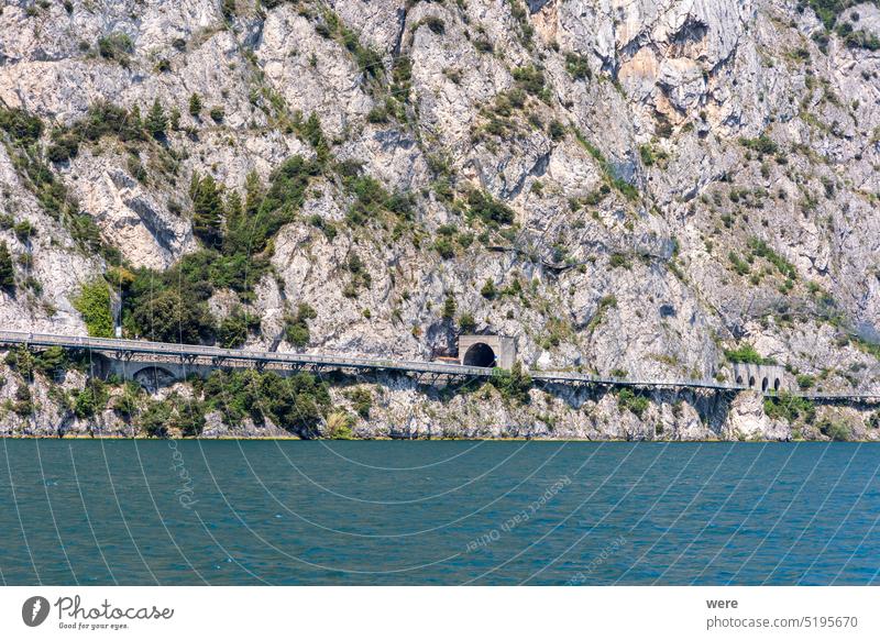 Blick vom Gardasee in Italien auf den Verlauf der Straße Gardesana Occidentale durch die Felswand am Westufer des Sees Kurs Westliche Gardesana h2o liquide