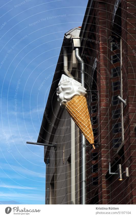 ein großes vanille softeis hängt oben am haus eistüte hörnchen waffel eiscreme eisdiele eiscafé werbeschild außenwerbung zeichen symbol wand fassade