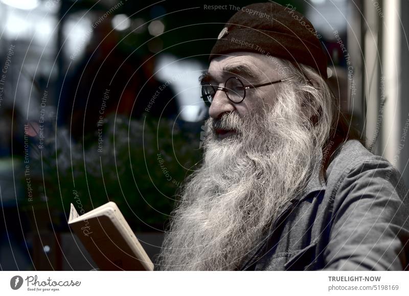 Alter Mann, Tolstoj-Kenner und -Fan, mit mächtigem weißen Rauschebart, Brille und schwarzer Kappe sitzt abends in einem Straßencafé und studiert sein Notizbuch