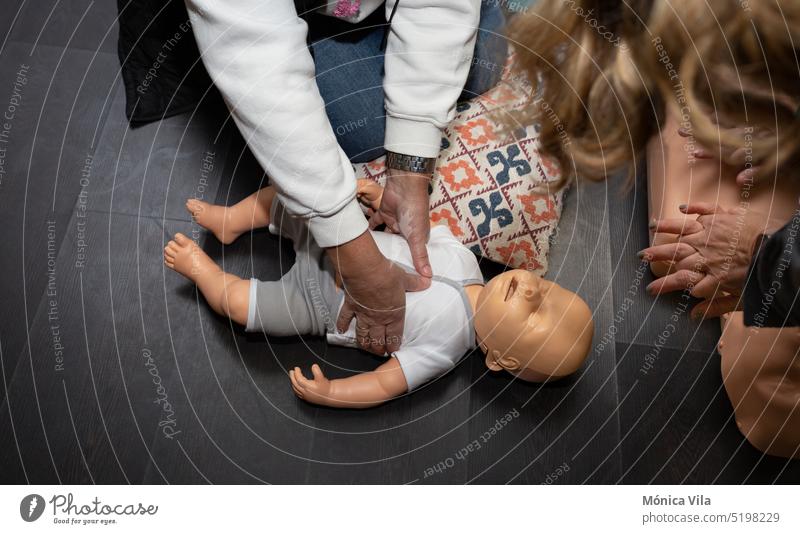 Drei Personen üben Erste Hilfe und Herz-Lungen-Wiederbelebung mit einer Erwachsenenpuppe und einer weiteren Puppe für die Wiederbelebung von Babys Dummy Kurs