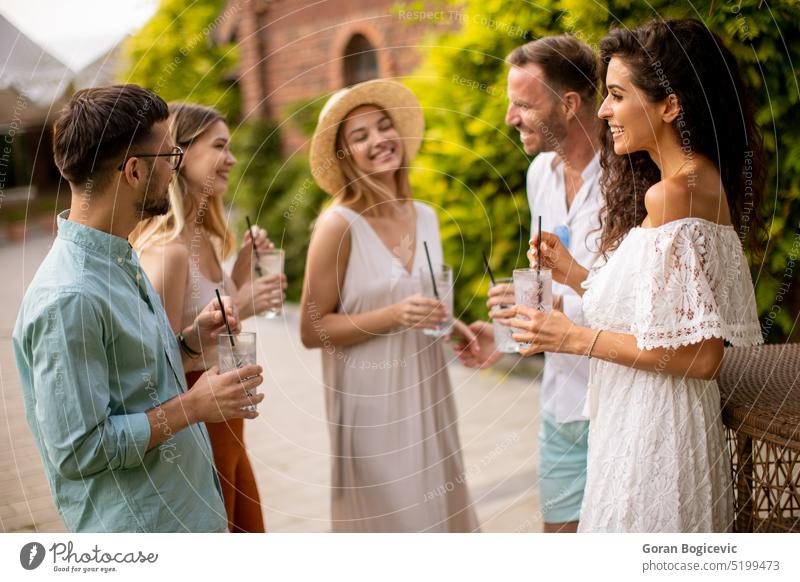 Eine Gruppe junger Leute versammelt sich im Freien, um die Gesellschaft der anderen zu genießen und sich mit einem Glas Limonade zu erfrischen junge Leute