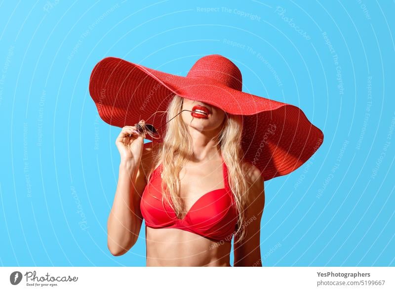 Sommerporträt einer Frau mit rotem Badeanzug und großem Sommerhut, isoliert auf blauem Hintergrund Strand Schönheit Bikini blond Körper BH randvoll schick cool