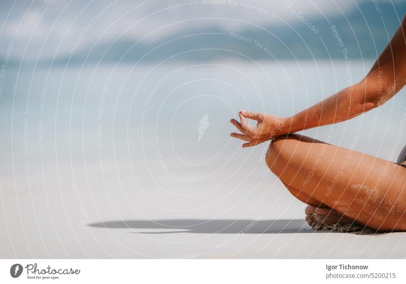 Rückansicht einer Frau Hände und Beine in meditierender Pose am Sandstrand. Tropischer Erholungsurlaub Strand Bikini MEER Rückseite türkis Seychellen Himmel