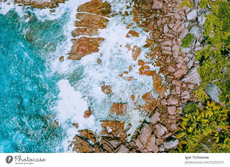 Luftaufnahme mit einer Drohne vom tropischen Strand Anse Cocos auf der Insel La Digue. Weiße Wellen plätschern gegen Granitfelsen an der Küste. Reisen und Urlaub Konzept