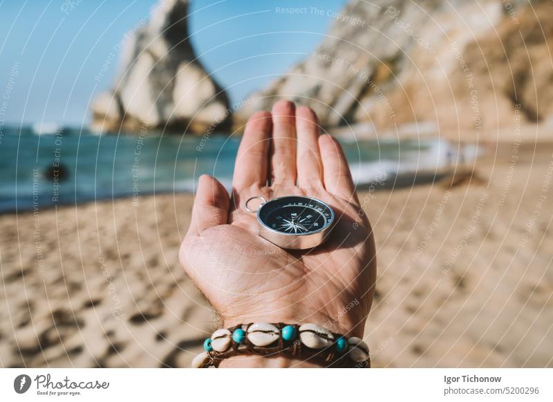 Mann mit Kompass, der das Konzept der Abenteuerlust symbolisiert, am Strand von Ursa, Sintra, Portugal Hand reisen Feiertag Fundstück MEER Lifestyle suchen
