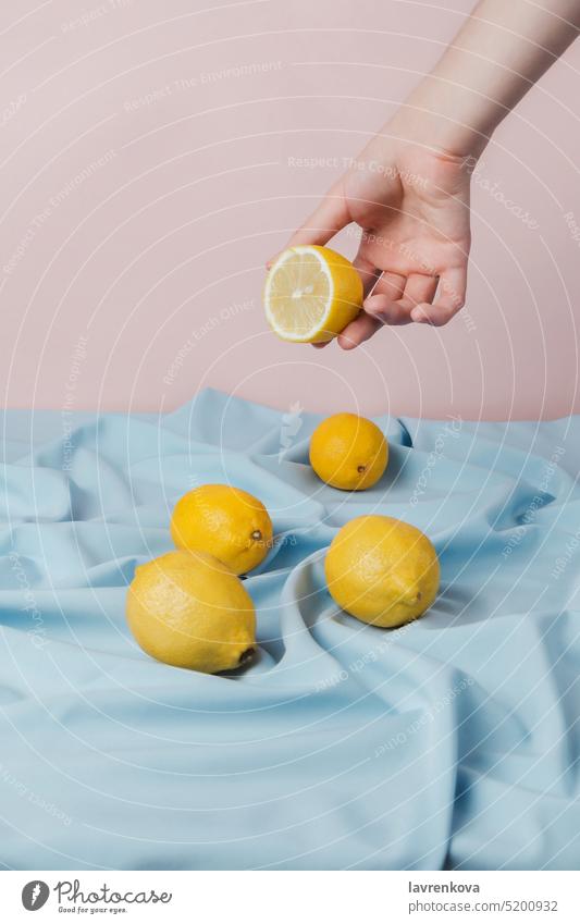 Weibliche Hand pflückt eine halbe Zitrone von einem mit blauem Vorhang bedeckten Tisch, frisch gelb Frucht geschnitten geschmackvoll süß saftig Zitrusfrüchte