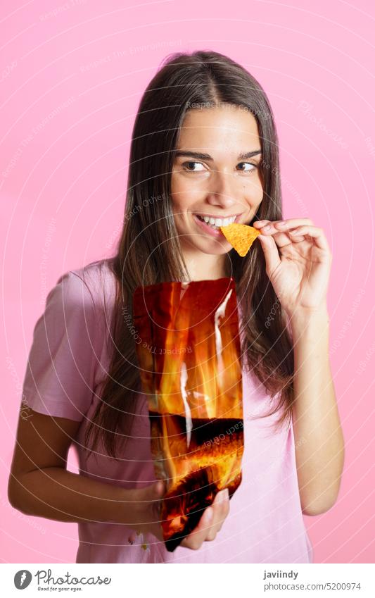 Frau in rosa T-Shirt isst Chips Lächeln positiv nacho Biss essen Snack Kartoffel knusprig Junk Food Fastfood ungesund lässig Paket geschmackvoll lecker