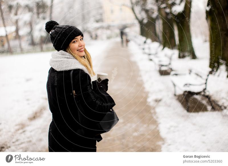 Junge Frau mit warmer Kleidung im kalten Winter Schnee trinken Kaffee zu gehen Erwachsener schwarz Bekleidung Mantel kalte Temperatur Handschuh Hut eine Person