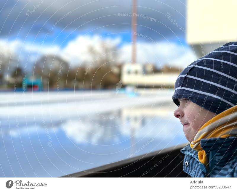 Kind schaut wartend auf die leere Schlittschuhbahn Schlittschuhe Schlittschuhlaufen Eisenbahn Eisfläche Winter Wintersport Außenaufnahme Freizeit & Hobby kalt