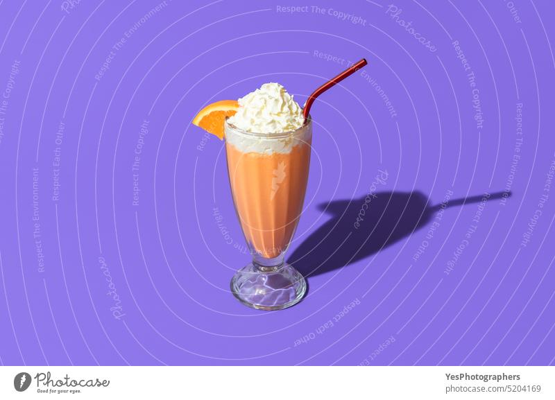Orangefarbener Milchshake isoliert auf einem lila Hintergrund. Milchshake Glas in hellem Licht oben Getränk Cocktail kalt Farbe Textfreiraum Sahne Küche Tasse