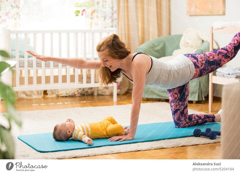 Junge Mutter trainiert zu Hause auf einer Matte mit Baby. Innenraum eines gemütlichen sonnigen Kinderzimmers. Frau übt Yoga zusammen mit Kind. aktiv Asana