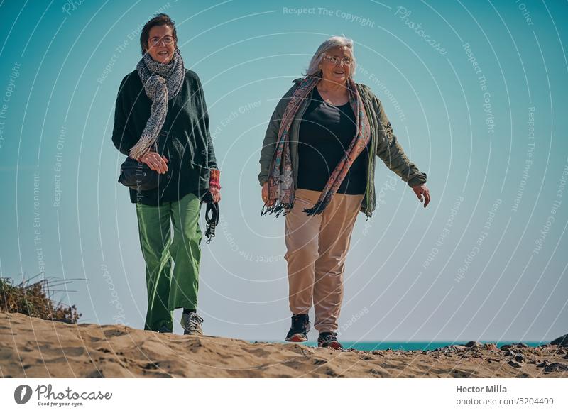 Zwei ältere Frauen schlendern an einem sonnigen Tag am Mittelmeerstrand Senior Strand Weiblicher Senior Mensch 60 und älter Außenaufnahme laufen alt Gesicht