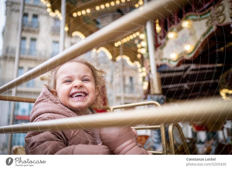 Lachendes Kleinkind im Kinderkarussell. Freude gold Karussell Kirmes Jahrmarkt lachen Mädchen Vergnügen Vergnügungspark Fahrgeschäfte Attraktion drehen Bewegung