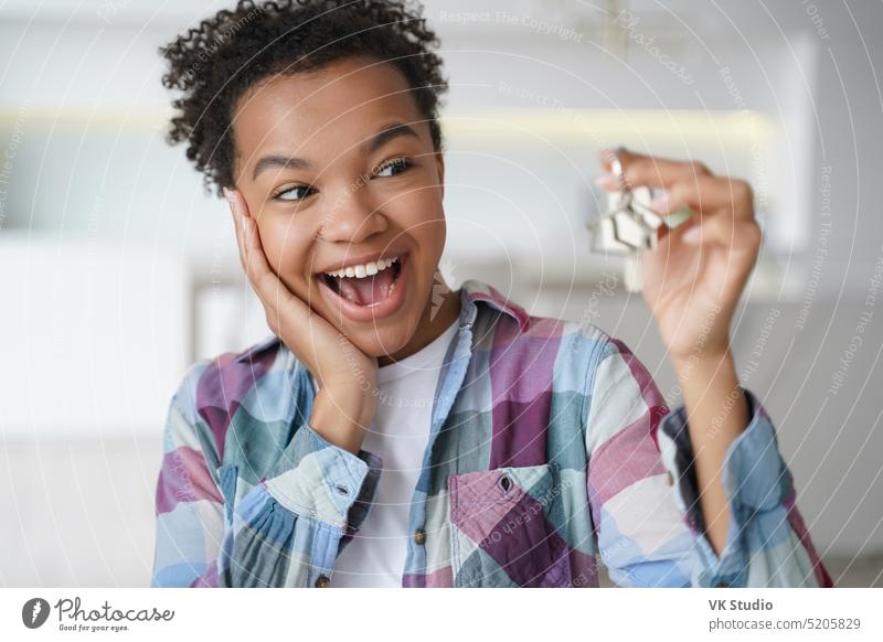 Aufgeregtes afrikanisch-amerikanisches Teenager-Mädchen, das die Schlüssel des ersten neuen Hauses zeigt. Immobilienmietdienst Taste heimwärts Afroamerikaner