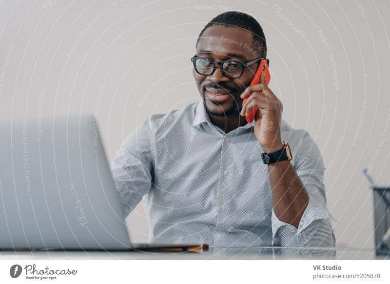Afroamerikanischer Geschäftsmann tätigt einen geschäftlichen Anruf, spricht am Telefon und bespricht die Arbeit am Laptop Afroamerikaner reden Büro Manager