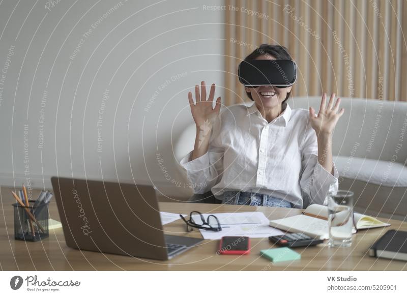Aufgeregte Geschäftsfrau mit Virtual-Reality-Brille bei der Arbeit im Büro virtuell Realität aufgeregt Frau Mitarbeiter VR Headset Schutzbrille berühren 3d