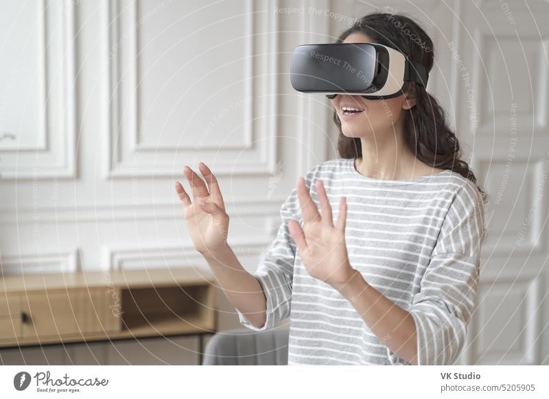 Junge beeindruckte brünette Geschäftsfrau, die mit virtueller Realität interagiert und eine VR-Headset-Brille trägt Frau Mitarbeiter Schutzbrille berühren Air