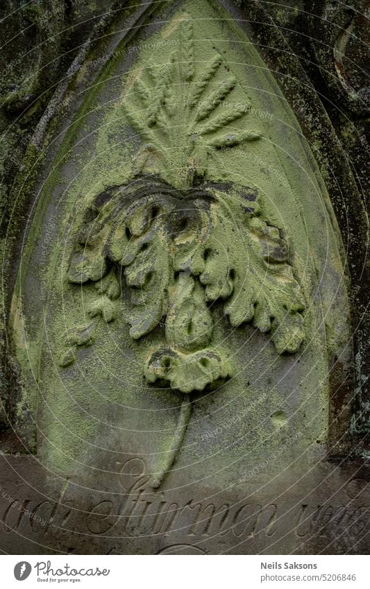 Grabstein mit Blumenschmuck auf dem alten Friedhof. antik Antiquität Antike Hintergrund behauen Christentum Nahaufnahme durchkreuzen Kruzifix desolat verblüht