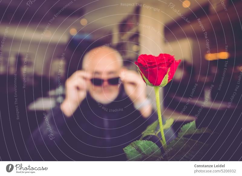 Rote Rose für einen Mann mit Sonnenbrille - im Restaurant. rot Blume Blüte unscharf weitsichtig Unschärfe blühen blühend Romantik Tischdekoration romantisch