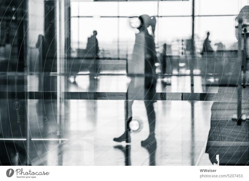 Mehrere Reisende mit und ohne Gepäck spiegeln sich in der Glasfassade des Flughafens Spiegelung Spiegelbild Fluggäste Fernreise warten Reflexion & Spiegelung