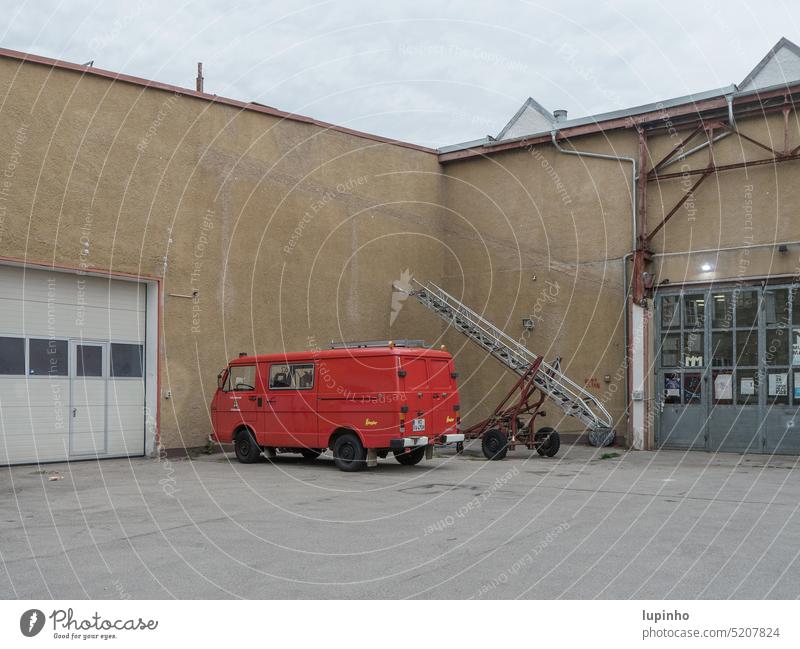 Altes Feuerwehrauto mit Leiteranhänger vor Garage rot Tore Gebäude Außenaufnahme Wand Menschenleer Haus Ecke Feuerwehrleiter Architektur Tag