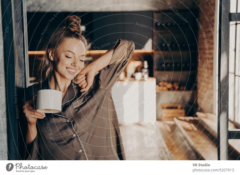 Glückliche schöne brünette Frau mit einer Tasse Kaffee in der Hand, während sie in der Küche steht jung hübsch Morgen Becher strecken Stehen Schlafzimmer