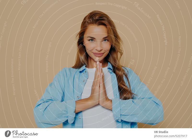 Junge Frau macht Namaste Geste isoliert auf beige Hintergrund Frieden meditieren Glück betend bitte friedlich hoffnungsvoll Hilfsbereitschaft Vergebung treu