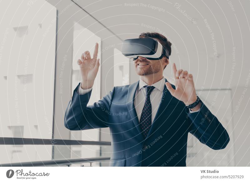 Aufgeregter Büroangestellter mit VR-Headset oder Virtual-Reality-Brille, der mit den Händen gestikuliert virtuell Realität aufgeregt Arbeiter Schutzbrille