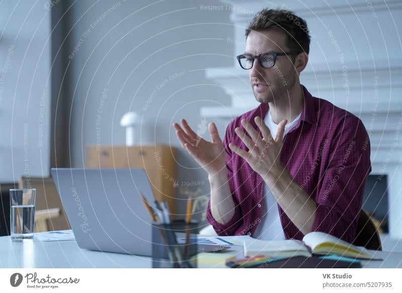 Junger konzentrierter deutscher Mann mit Brille und Freizeitkleidung, der an einem virtuellen Online-Meeting teilnimmt entfernt Bildung Video Anruf Laptop