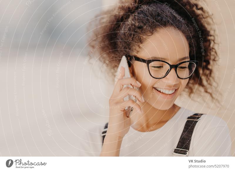 Close up Porträt von fröhlichen Frau mit knackigen Haaren, zufrieden mit Tarifen für Telefonanruf, konzentriert sich nach unten, hält moderne Smartphone, Anrufe an die beste Freundin, diskutiert die neuesten Nachrichten. Technologie-Konzept