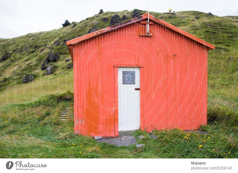 Holzhütte in orangefarbener Farbe und weißer Tür. Island farbenfroh Hintergrund Sommer Landschaft Tourismus retro Außenseite im Freien ländlich rustikal rot