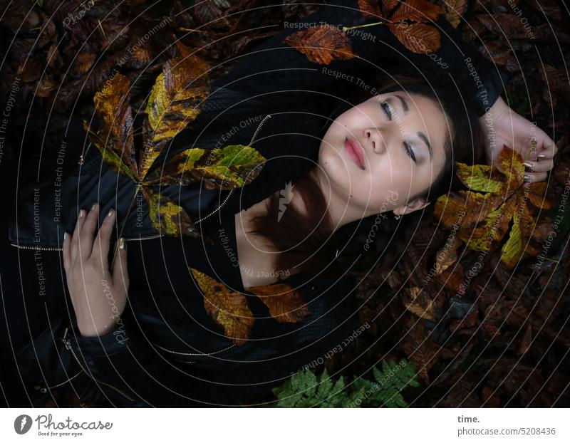 liegende Frau, das Herbstlaub genießend Oberkörper Porträt geschlossene Augen Ruhe Vogelperspektive Starke Tiefenschärfe Schatten Dämmerung Außenaufnahme
