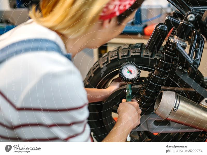Mechanikerin prüft den Luftdruck der Motorradreifen unkenntlich Frau Überprüfung Air Druck Reifen Rad Manometer arbeiten Fabrik Garage Arbeiter Ventil Bremse