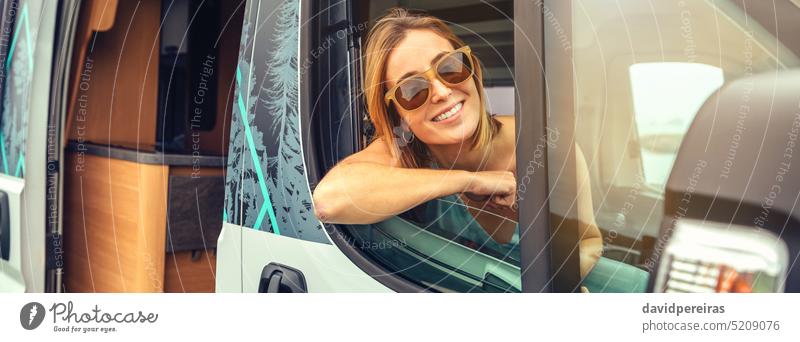 Junge Frau mit Sonnenbrille sitzt im Wohnmobil und lehnt sich an die Tür Glück jung Kleintransporter Sitzen Lehnen Transparente Netz Kopfball Panorama