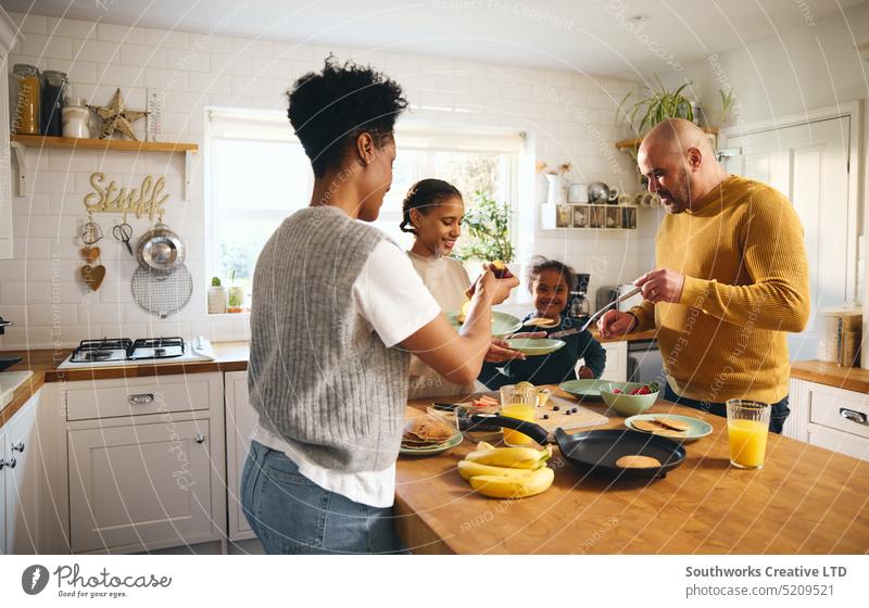 Familie macht Pfannkuchen zum Frühstück Junge Down-Syndrom machen Eltern vier schwarz Küche Lebensmittel rassenübergreifend Lachen Freude Spaß Arbeitsplatte
