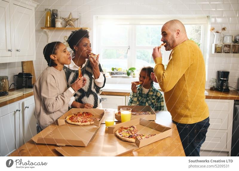 Familie isst Pizza zum Mitnehmen zu Hause und lacht essen Imbissbude Abendessen Takeout heimwärts Lachen Genuss rassenübergreifend Junge Down-Syndrom Mann Frau