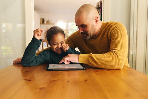 Mehrrassiger Vater und Sohn mit Down-Syndrom nutzen digitales Tablet für Hausaufgaben Vatertag digitales Tablett Lifestyle rassenübergreifend Mann Junge Kind