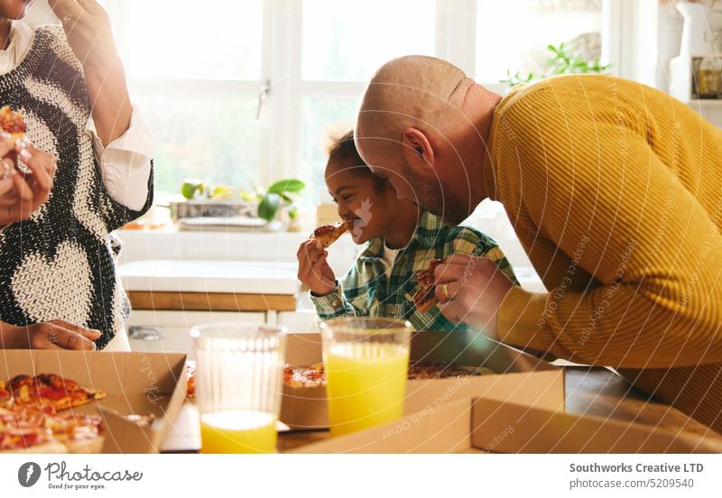 Junge mit Down-Syndrom genießt Pizza zum Mitnehmen mit seiner Familie essen Imbissbude Vater Abendessen Genuss rassenübergreifend Lächeln heiter Glück Lachen