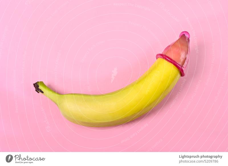 Kondom auf Banane mit rosa Hintergrund. Konzept des sexuellen Schutzes. Symbol Sexualerziehung sexuelle Fragen AIDS Verhütungsmittel Erektion