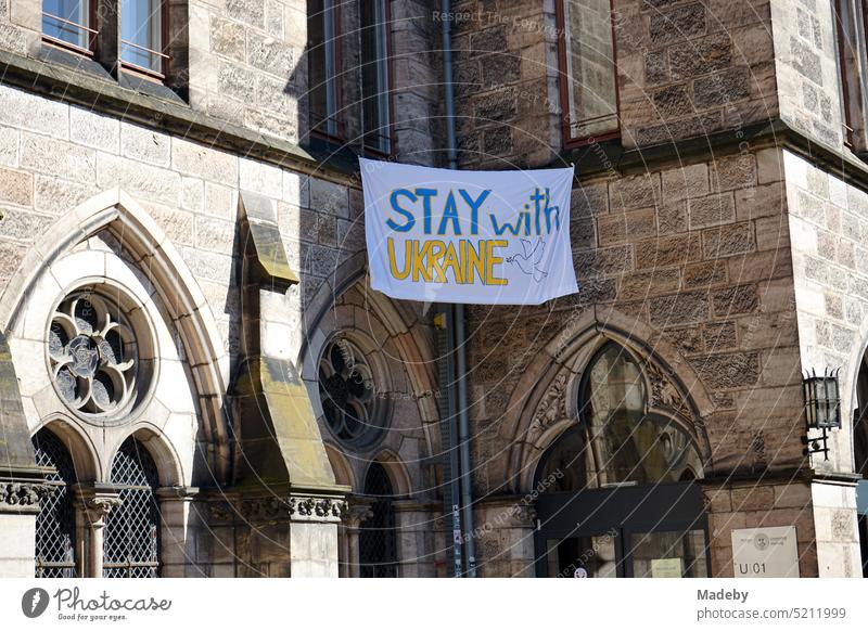 Stay with Ukraine Banner aus Stoff an der alten Fassade der Liebfrauenbasilika im Herbst bei Sonnenschein in der Altstadt von Maastricht an der Maas in der Provinz Limburg der Niederlande